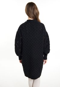 Maglione nero lavorato a maglia oversize con un motivo a diamante texturizzato, maniche a lunghezza completa e polsini e orlo a coste.