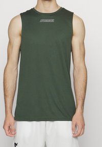 Ciemnozielona bezrękawnik sportowy z okrągłym dekoltem, z białym logo "HUMMEL" na klatce piersiowej, wykonany z lekkiego materiału.