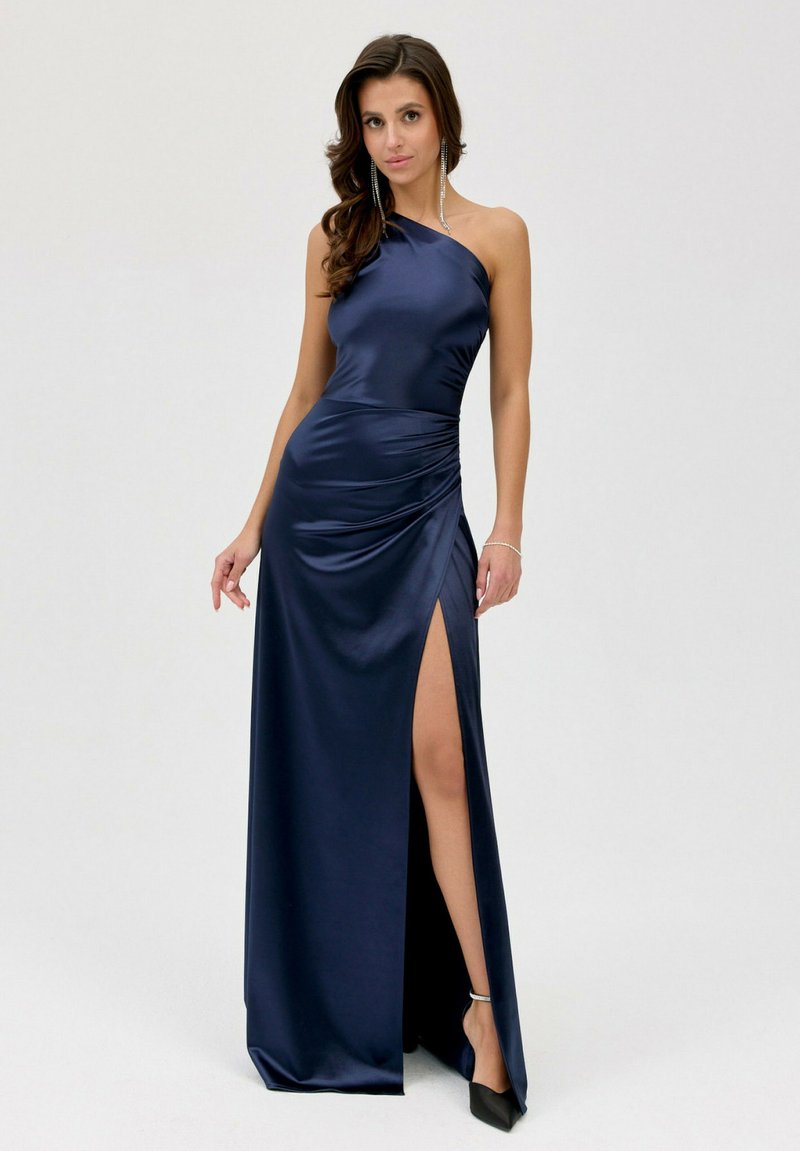 Námořnická saténová večerní šaty s jedním ramínkem, na boku nařasené, s vysokým rozparkem a hladkou texturou. Nosí se s černými podpatky a stříbrnými náušnicemi.