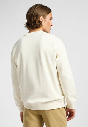 Kermanvärinen collegepaita, jossa on pyöreä kaula-aukko ja pitkät hihat. Pehmeä kangas, jossa on sileä rakenne. Ribbaavat hihat ja helma, minimalistinen muotoilu.