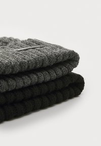 Three folded knit scarves in varying shades: top in dark grey with a ribbed texture, middle in grey, and bottom in black.