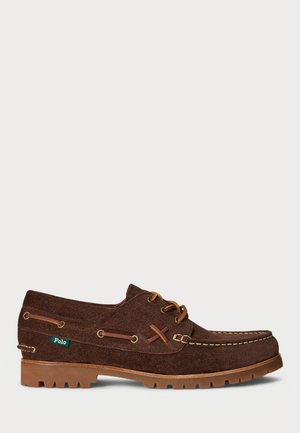 Zapato náutico de cuero ante marrón con cordones color canela, costuras en contraste, suela de goma y pequeña etiqueta verde de la marca Polo en el lateral.