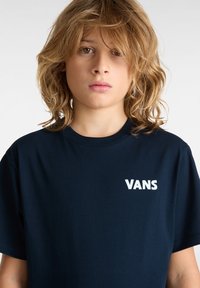 Navy modrá bavlněná tričko s krátkým rukávem a bílým logem "VANS" na levé části hrudi. Hladká textura, standardní střih.