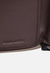 Vera pelle marrone con superficie texture, dotata di chiusura con zip e etichetta goffrata "Vera Pelle".
