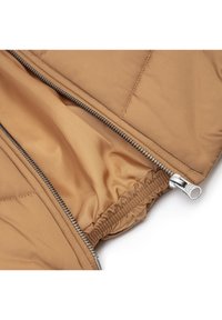 Chaqueta acolchada marrón con forro interior, que presenta una cremallera plateada y detalles elásticos en los puños. Costuras planas y textura suave.