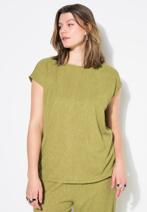 Top de manga corta color verde oliva con un corte relajado, que presenta una superficie texturizada y un brillo sutil. Combinado con pantalones a juego.