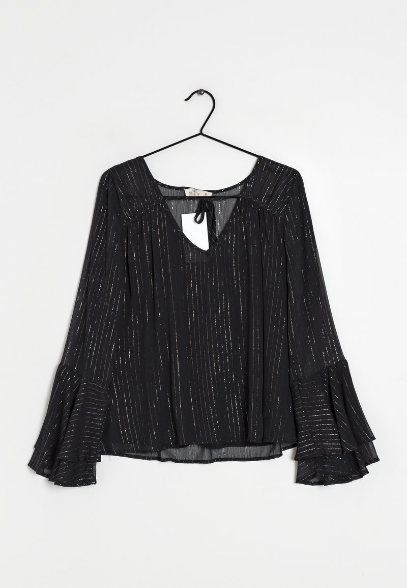 Blouse noire avec de longues manches évasées, présentant un décolleté en V et un détail en trou de serrure. Le tissu a des rayures verticales dorées métalliques pour une texture supplémentaire.