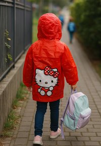 Child wearing a red raincoat with a Hello Kitty design, carrying a pastel purple and blue backpack, walking on a paved sidewalk.