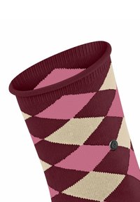 Skarpetki robione na drutach z wzorzystym deseniem w kolorach bordowym, różowym i kremowym. Fakturowana tkanina i ściągacz na górze. Widoczna logo znanej marki.