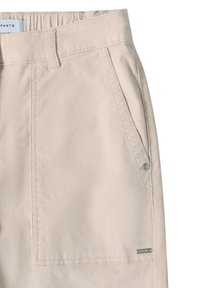 Béžové kalhoty s elastickým pasem, bočními kapsami a malým kovovým logem. Tkanina má hladkou texturu a upravený střih.