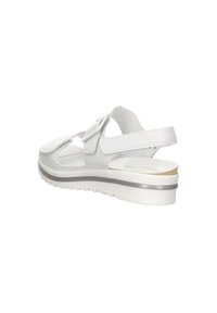 White sandal with adjustable straps, soft texture, and a lightweight wedge sole featuring a subtle silver accent. Open design for breathability.