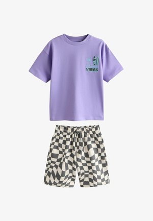 Ljubičasta majica kratkih rukava s natpisom "Los Angeles Vibes" i dizajnom daske za surfanje u kombinaciji s crno-bijelim kratkim hlačama s uzorkom iskrivljene šahovnice.