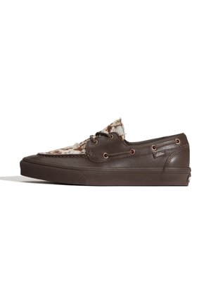 Baskets basses en cuir marron avec un design à lacets et une languette en fourrure à motif peau de vache, logo Vans sur le côté et semelle en caoutchouc épaisse.