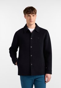 Giacca nera in lana con colletto a punta, chiusura con bottoni e due tasche frontali. Caratterizzata da una texture liscia e un discreto dettaglio con logo.