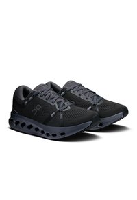 Chaussures de sport noires avec une tige en mesh respirant, détaillées avec des accents gris, une semelle rembourrée et des découpes circulaires pour la ventilation.