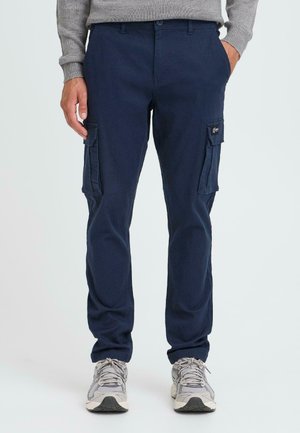 Navy cargo pants made of cotton, featuring two side pockets and a textured finish. Paired with gray athletic shoes.