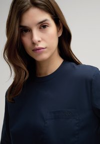 Marineblaue, kurzärmelige Hemd mit Rundhalsausschnitt und einer Brusttasche mit geprägt "JOOP!"-Logo. Glatte Oberfläche, minimalistisches Design.