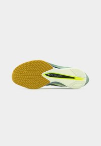 Σόλα ενός παπουτσιού για τρέξιμο Nike Flyplate με κίτρινο μοτίβο πρόσφυσης, λευκή ενδιάμεση σόλα και πράσινες λεπτομέρειες σε λευκό φόντο.