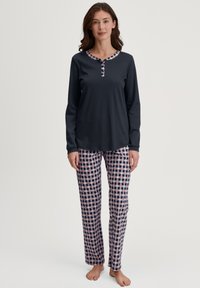 Langärmliges navy-blaues Oberteil mit einem gemusterten Kragen und einer Knopfleiste, kombiniert mit karierten Hosen in Navy, Rot und Weiß. Lässiges Design.