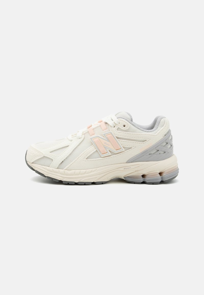Basket de sport blanche avec tige en mesh, accents rose et gris, semelle texturée et un logo "N" proéminent sur le côté. Design orienté vers la performance.