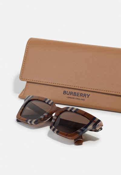 Burberry napszemüveg geometriai barna kerettel, csíkozott karokkal, egy barna textúrált bőrtokkal párosítva.