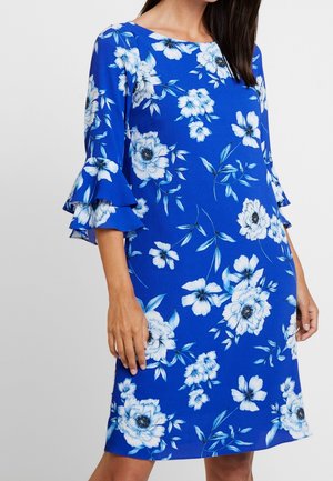 Vestido floral en tela azul brillante, con patrones de flores blancas y azul claro, mangas con volante hasta tres cuartos y escote redondeado.