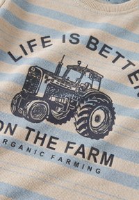 Niebiesko-beżowa dzianina w paski z grafiką vintage traktora i wyrazistym czarnym napisem "ŻYCIE JEST LEPSZE NA FARMIE."