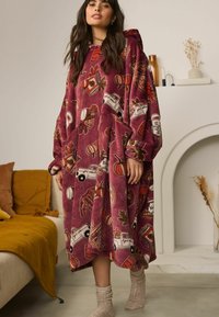 Oversized kastanjebruine hoodie-deken met een herfstthema print, met pompoenen, bladeren en vrachtwagens. Zacht, textuurstof. Grote voorkant zakken.