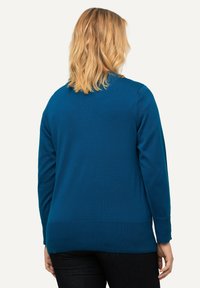 Tealfärgad tröja med lång ärm, ribbat nederkant och manschetter, tillverkad av mjukt material, med en avslappnad passform och enkel design.