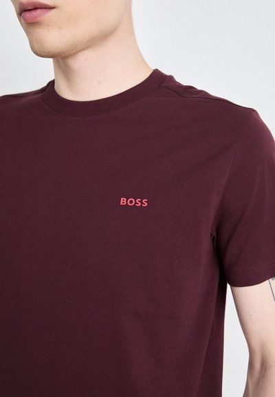 T-shirt en coton bordeaux avec un col rond et des manches courtes, orné d'un logo "BOSS" brodé rouge contrastant sur la poitrine.