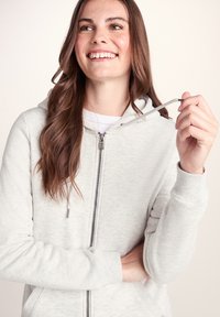 Light gray zip-up hoodie made of soft fabric, featuring a hood, ribbed cuffs, and drawstring accents. Smooth texture with a casual design.