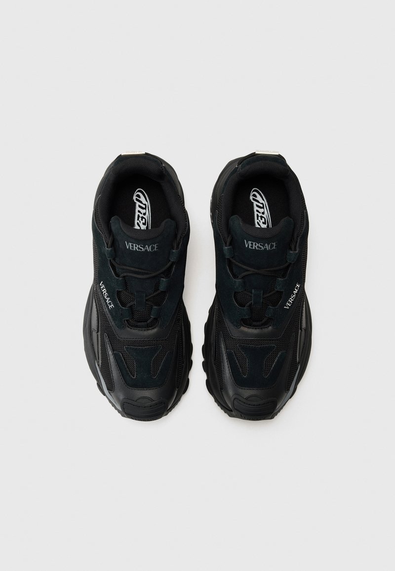 Zwarte sneakers met een mix van suede en mesh materialen, opvallende branding, textuuraccenten en een gedurfde, chunky zoolontwerp.