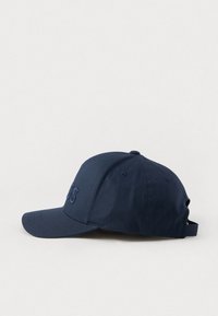 Mørkeblå baseballcaps laget av stoff med en jevn tekstur, med tonal brodert logo foran og en justerbar stropp bak.