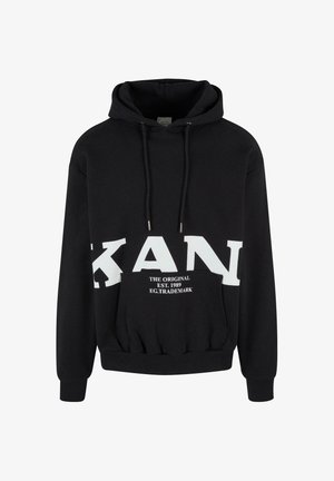 Sudadera negra con bolsillo canguro, que presenta un gran logo blanco en el pecho y cordones con puntas de plata. Textura de tela suave.