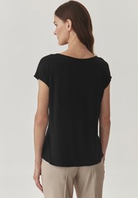 Haut noir à manches courtes avec une coupe décontractée, encolure ronde et texture douce. Assorti à un pantalon à rayures légères.