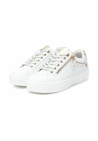 Zapatillas blancas con textura acolchada, detalles en plateado y un cierre lateral con cremallera. Presentan una suela blanca plana y ojales metálicos para los cordones.
