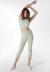 Ljusgrön sportcroppströja och midikalv leggings i mjukt tyg. Har en figurnära design med ett brett midjeband och inga synliga mönster.