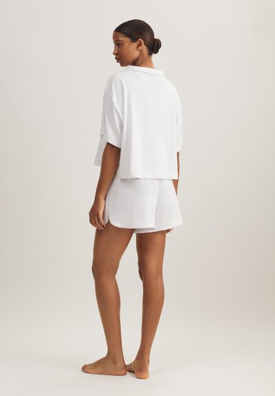 Σετ λευκής ρόμπας από περκάλι, που περιλαμβάνει ένα φαρδύ τοπ με κοντά μανίκια και ταιριαστό σορτσάκι, με άνετη εφαρμογή και πλαϊνά σχισίματα για άνεση.