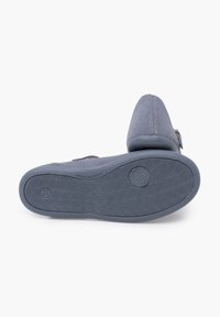 Zapato de ante gris con puntera redondeada. Presenta una suela de goma texturizada y un detalle de hebilla. Diseñado para la comodidad y facilidad de uso.
