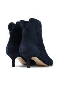 Granatowe zamszowe botki za kostkę z wyprofilowanym wierzchem, 6-centymetrowymi obcasami w szpilce i gładką teksturą. Posiada zaokrąglone akcenty na górnych krawędziach.