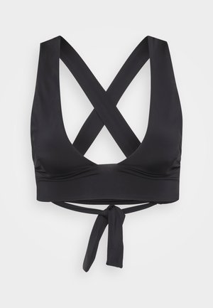 Black crop top with a deep V-neck, crisscross back straps, and a tie detail at the waist, made of smooth material.