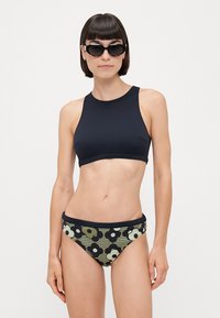 Fekete sportos bikini felső, mintás bikini alsóval párosítva, amely nagy virágmintákkal rendelkezik zöld és sötétkék színben, sima textúrával és sportos dizájnnal.