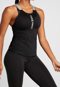 Zwarte atletische tanktop met grijze verstelbare bandjes, met het "NIKE PRO"-logo in het wit in het midden. Gemaakt van ademende, rekbare stof.