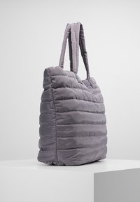 Puffy gray tote bag with horizontal quilting and two padded shoulder straps, displayed on a white pedestal against a plain background.