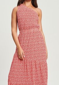 Robe à motifs floraux rouges avec un design à une épaule, taille élastique et jupe fluide. Fabriquée en tissu léger pour plus de confort.