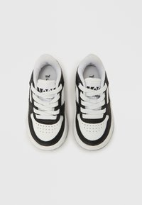 Fekete-fehér sportcipők sima bőr felsőrésszel, kontrasztos csíkokkal, párnázott szegéllyel és fehér fűzőkkel. Lyukacsos orr-rész a szellőzés érdekében.