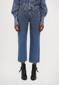 Light blue denim jeans with a relaxed fit, featuring a gradient of small metallic studs near the bottom. Finished with a straight cut and frayed hem.
