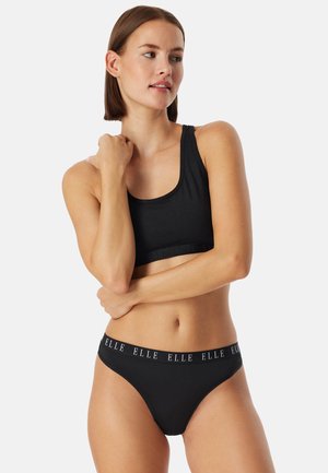 Svart sport-bh med breda axelband och resårband. Matchande svarta bikinitrosor med varumärkeslogga på midjebandet. Mjukt tyg, minimalistisk design.