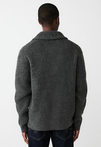 Gray knitted sweater with a shawl collar, textured fabric, long sleeves, and a relaxed fit. Visible seams and a hemline that curves slightly.