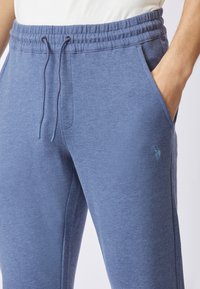Pantaloni jogger blu realizzati in tessuto morbido, con vita elastica e cordino, tasche laterali e un piccolo logo.
